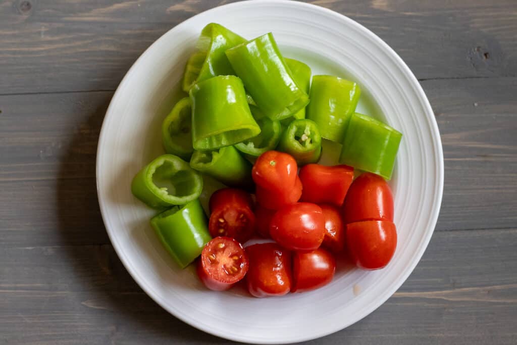 Halved cherry tomatoes and green pepper pieces on a plate.