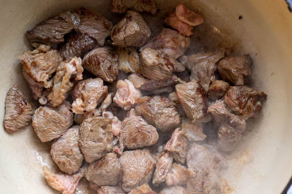 Diced beef browning in a Dutch oven.