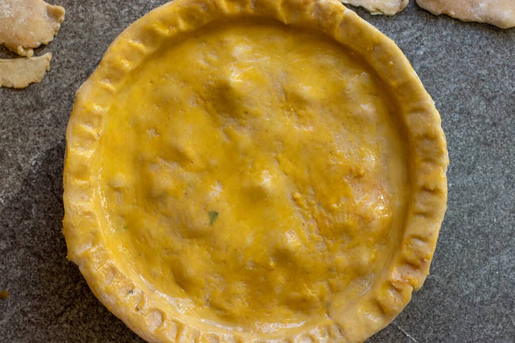 Steak pie covered with shortcrust pastry, brushed with egg yolk, and ready for the oven.