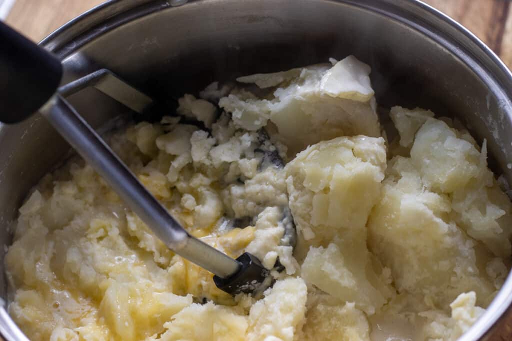 Mashing the potatoes with a masher.
