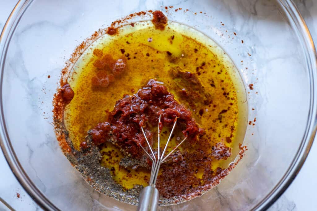 Olive oil, milk, tomato paste, red pepper paste, and seasoning are placed in a glass bowl.