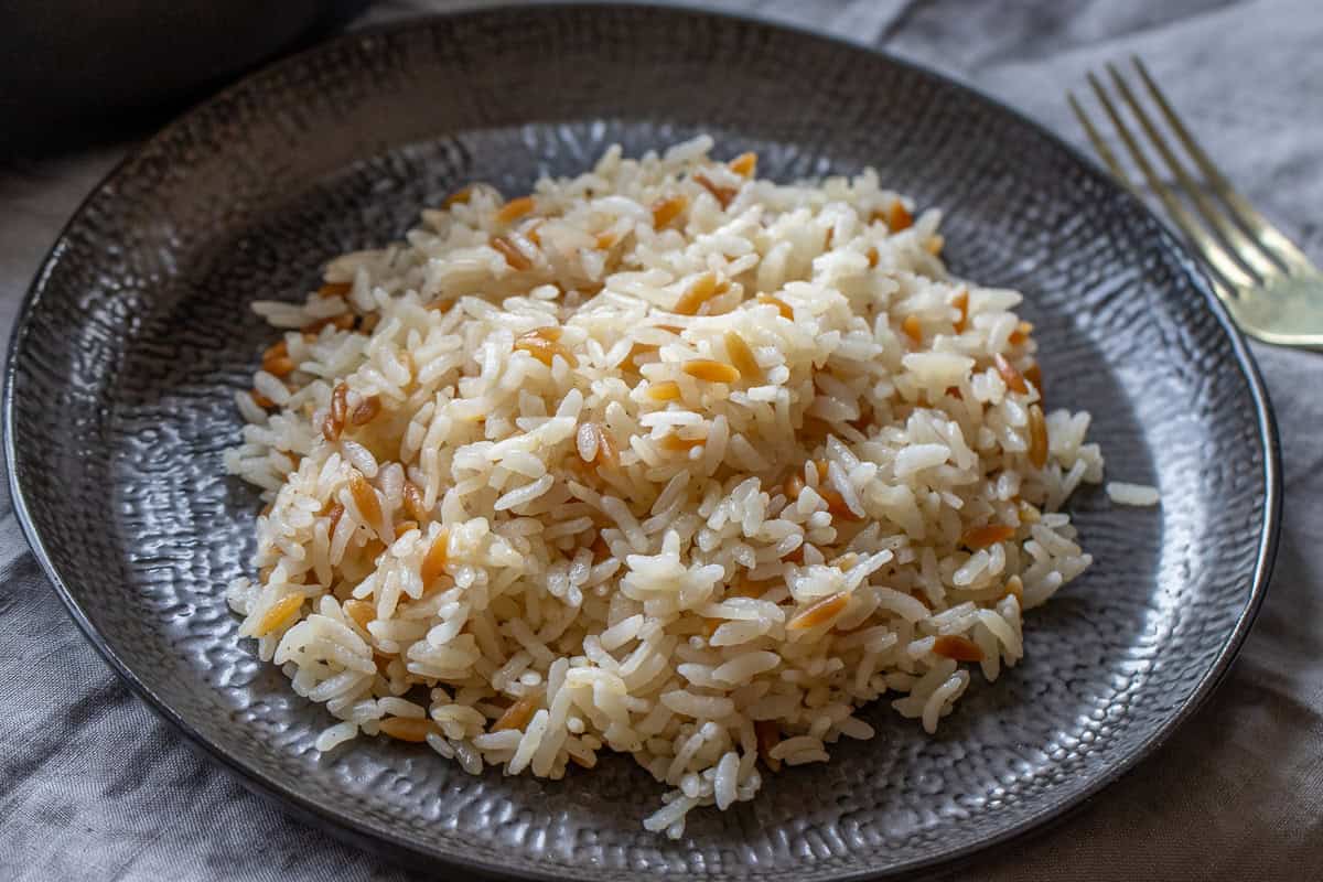 Rice pilaf on a black plate.
