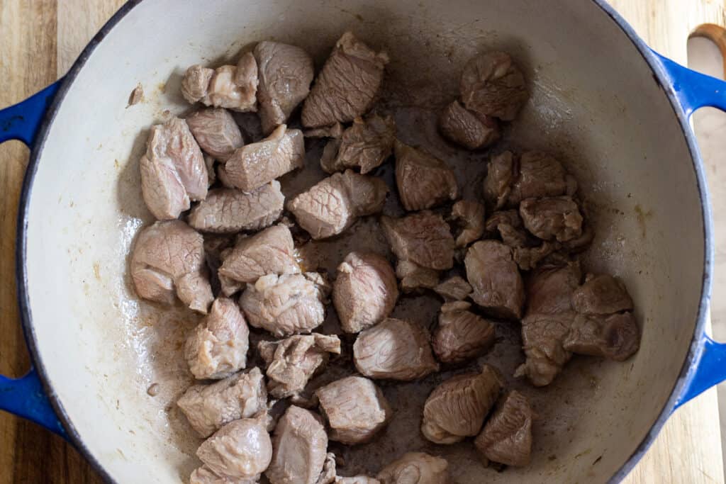 Pieces of lamb browning in a Dutch oven.