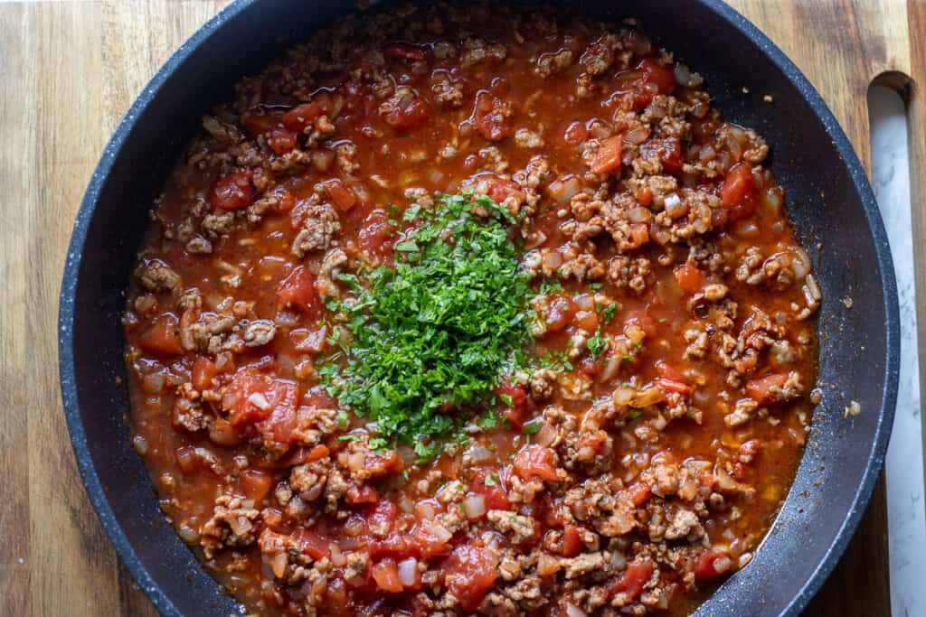 Chopped parsley is added to the cooked meat sauce.