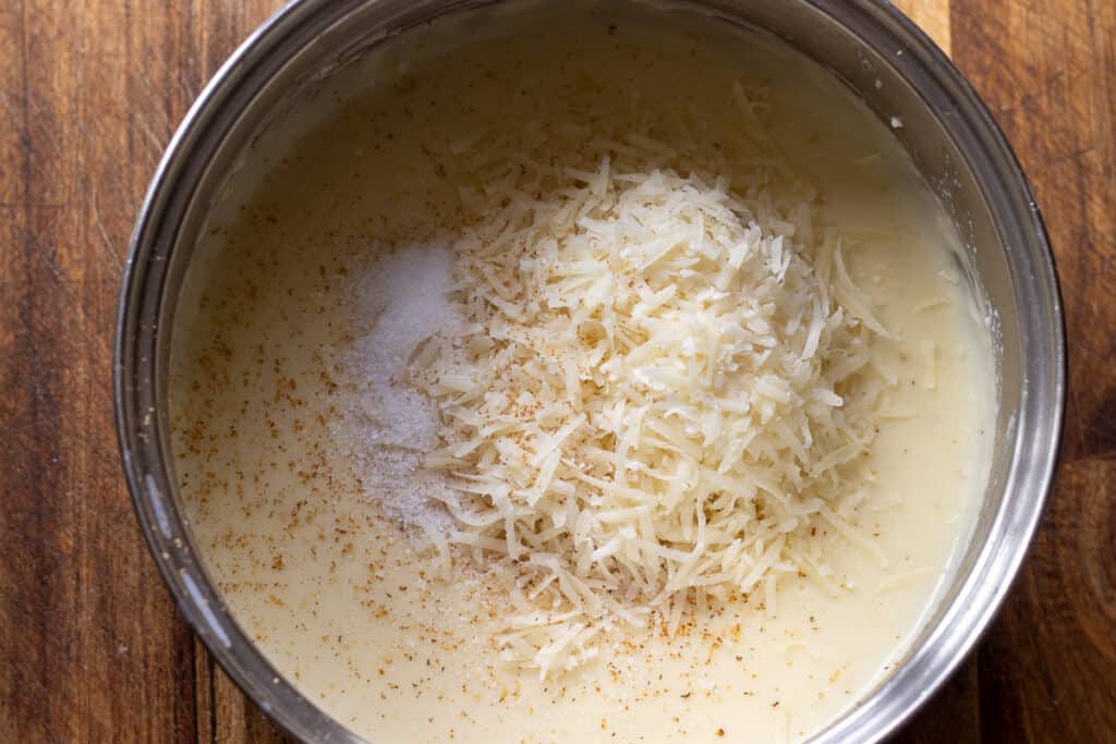 Salt, nutmeg, and grated parmesan are added to béchamel sauce.