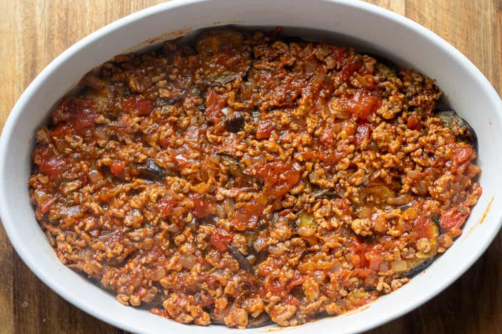 Half of the meat filling is layered on top of eggplants.