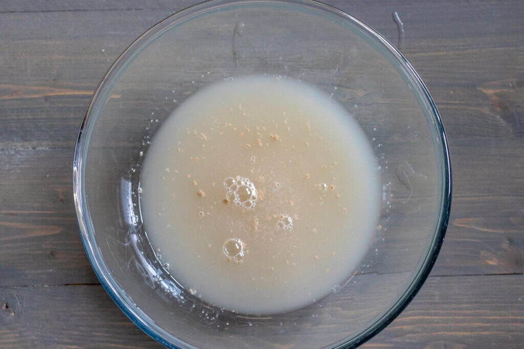 Water, sugar, and yeast are mixed in a bowl.