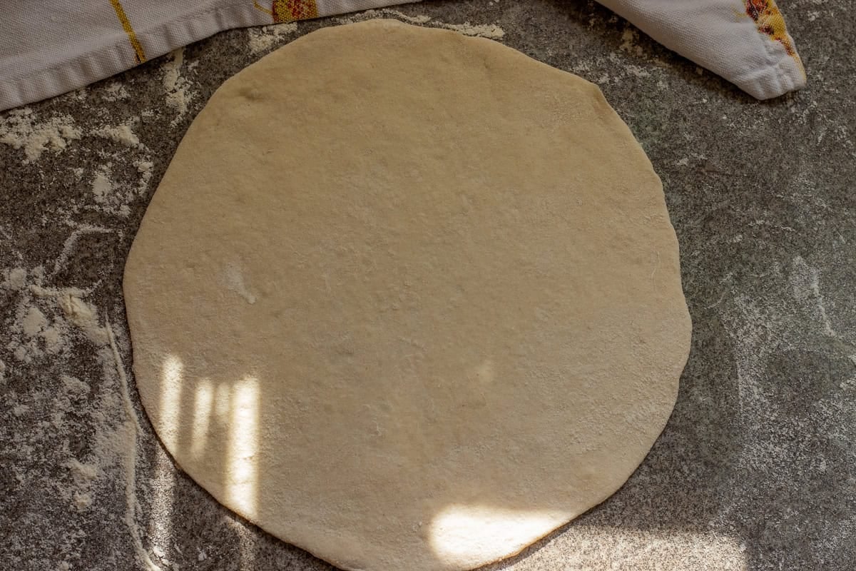 A dough ball is rolled out into a circle.