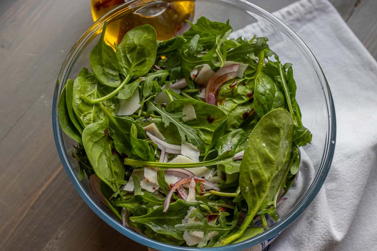 Salad made with arugula and spinach leaves, served in a glass bowl.