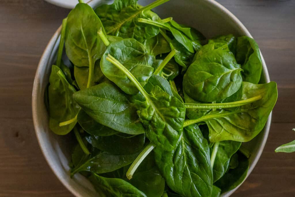 Washed and dried baby spinach leaves in a bowl.