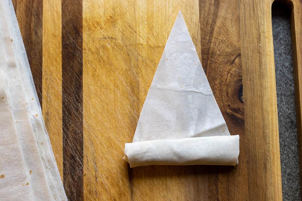 The wide edge of the yufka folded over the filling and rolled halfway up.