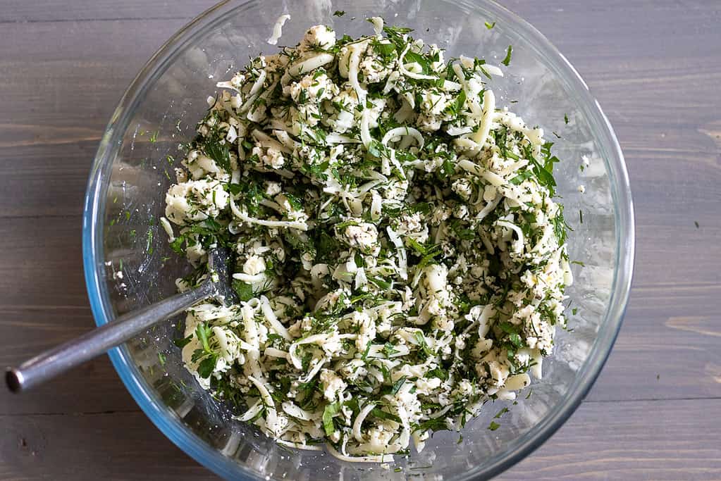 The cheese and herb filling mixed together in a glass bowl.