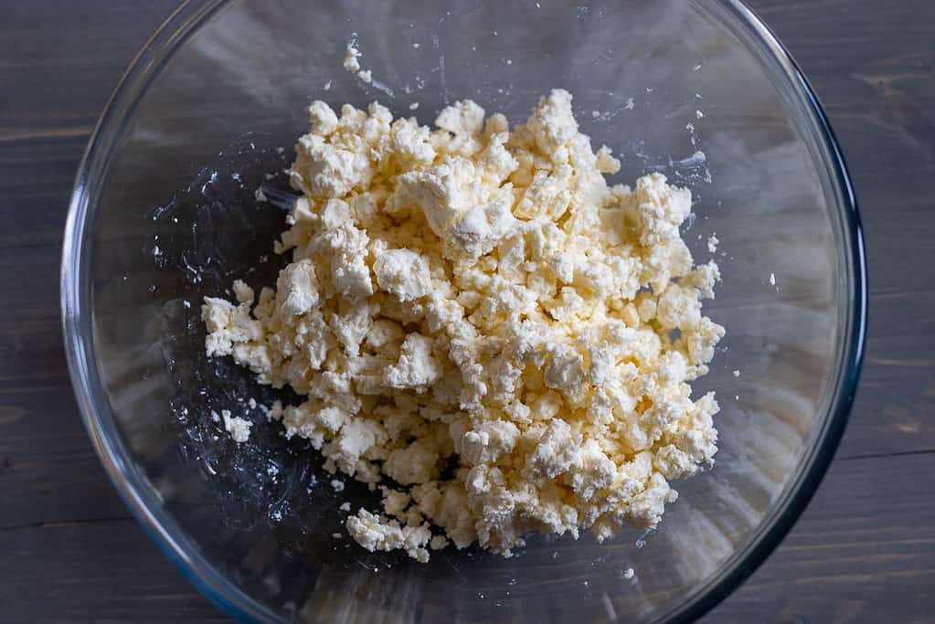 Crumbled feta cheese in a glass mixing bowl.