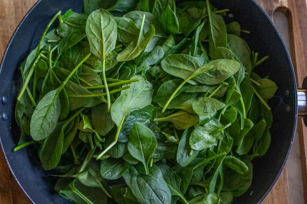 Fresh spinach leaves are added to the pan.