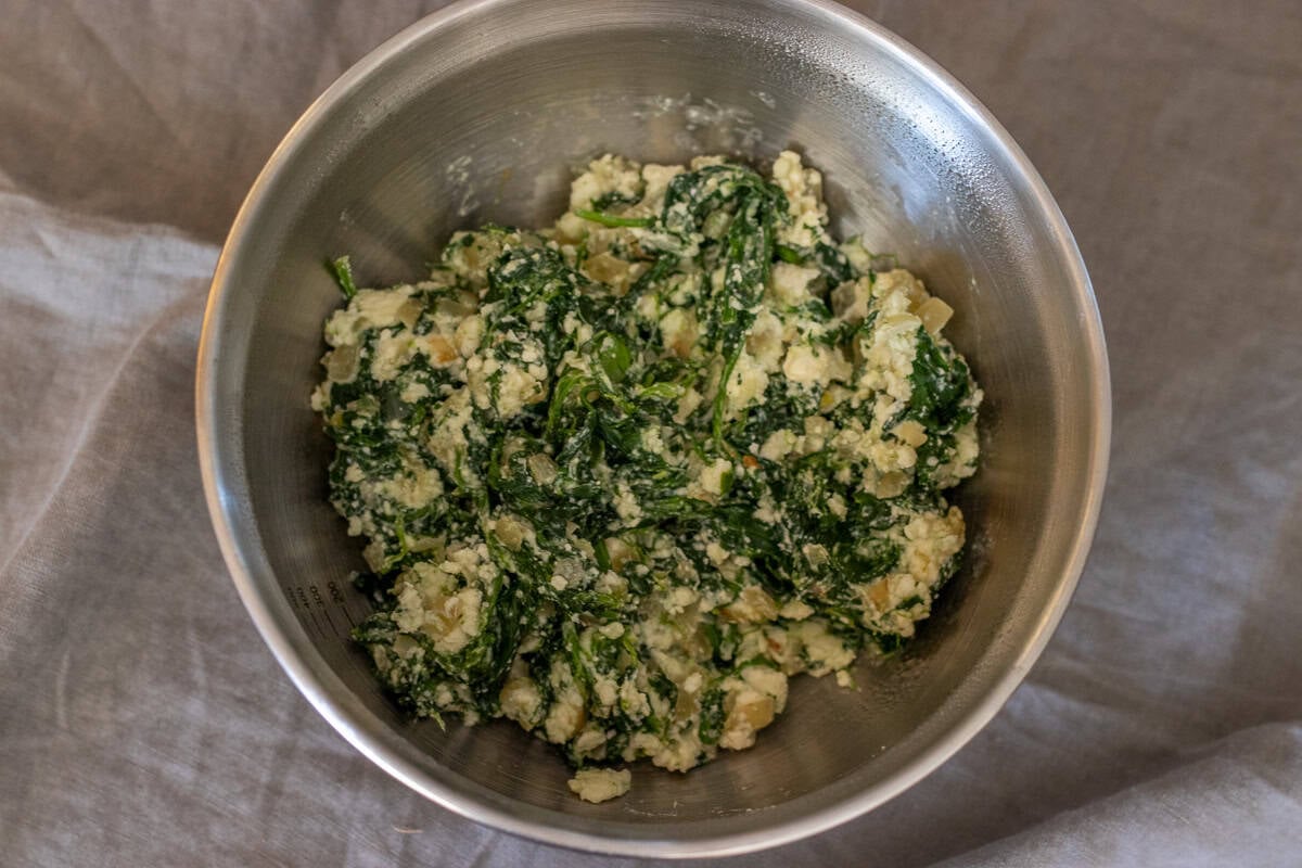 Crumbled feta cheese is mixed with sautéed spinach.