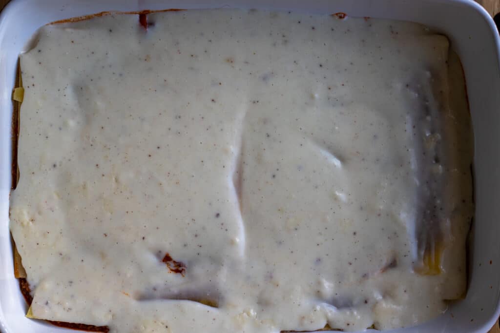 Bechamel sauce is spread on lasagna sheets.