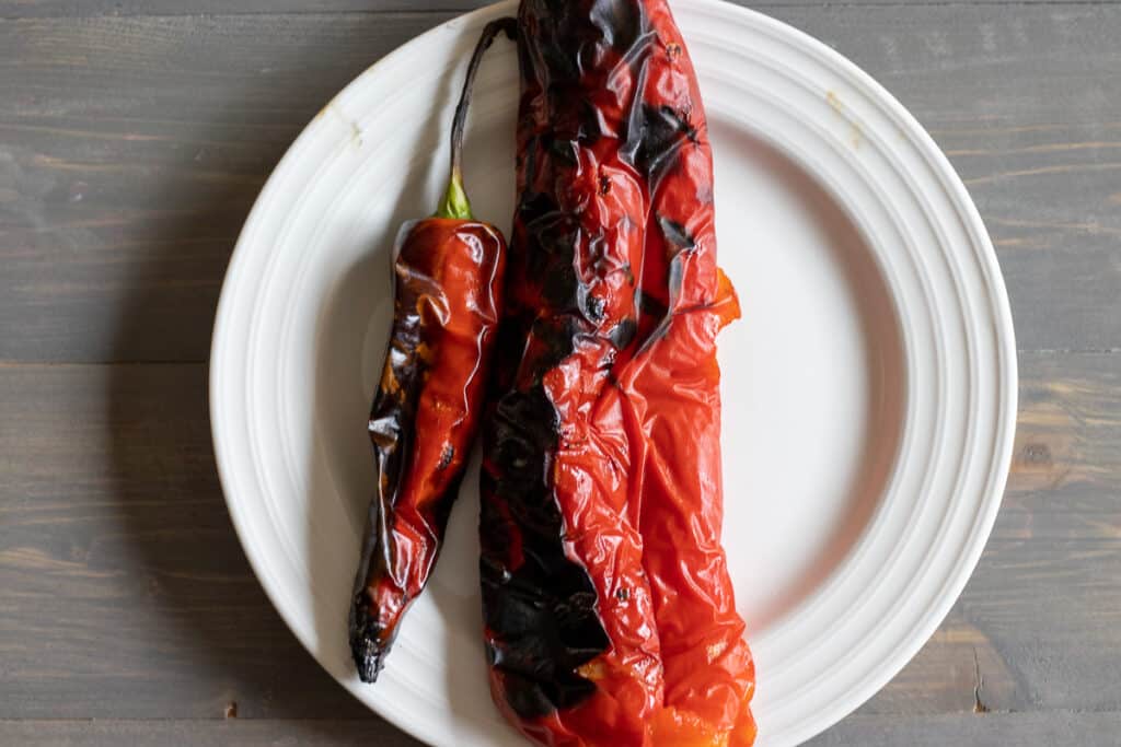 A red pepper and a chili charred on a grill.