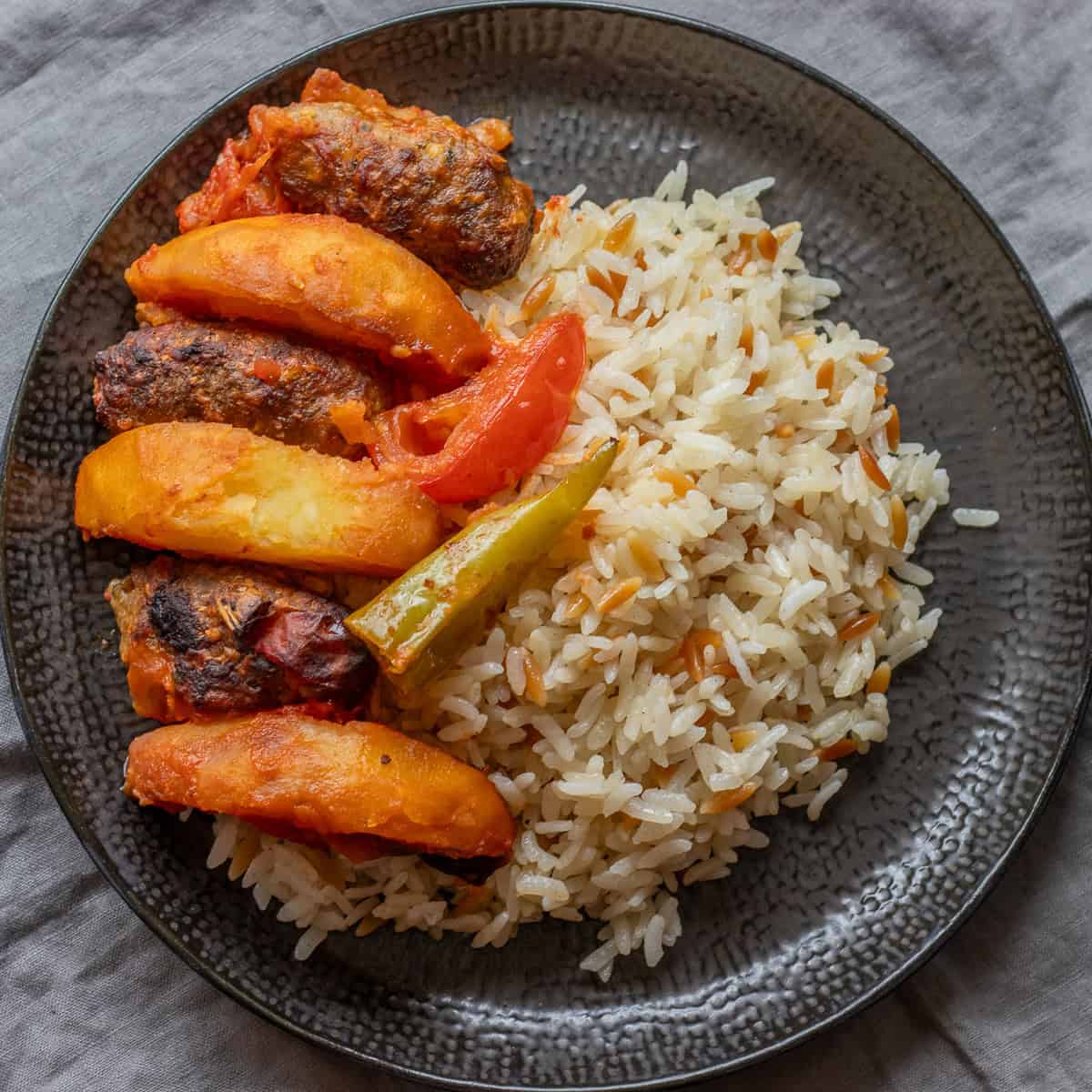 İzmir köfte with potato wedges, peppers and tomato, served with rice.