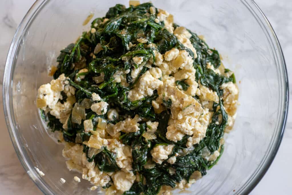 Crumbled feta cheese is mixed with sauteed spinach.