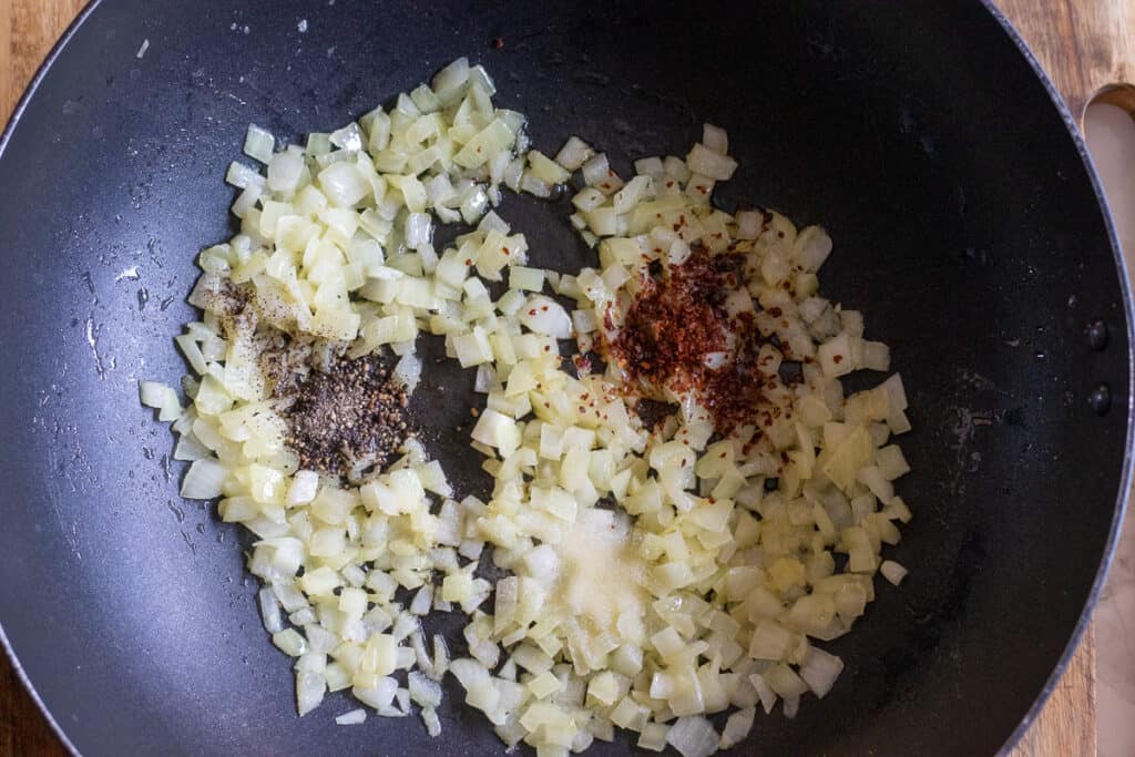 Salt, pepper and chili are added to the sautéed onions.