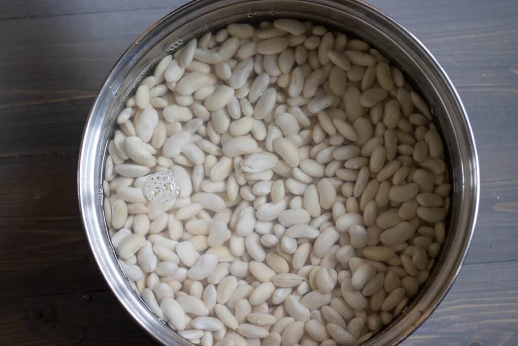White beans cooking in a pot of water.