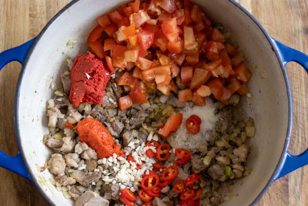 Tomatoes, tomato paste, and pepper paste stirred into the pan with the lamb.