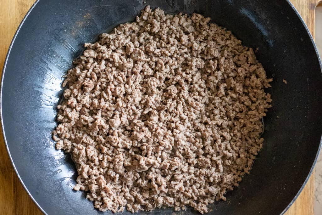 Ground beef browning in a wok.