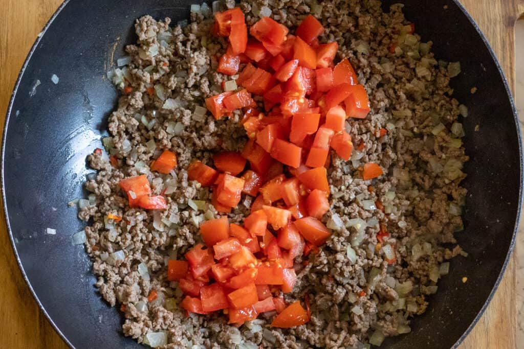 Diced tomatoes are added to the ground beef mixture.