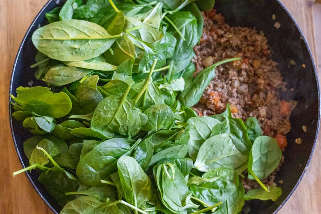 Baby spinach leaves are added to the pan.