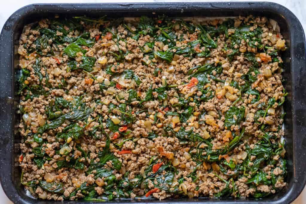 Meat and spinach filling is spread on top of the phyllo pastry.