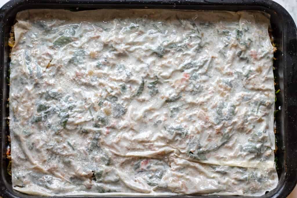 Layering the rest of the phyllo sheets on top of the filling.