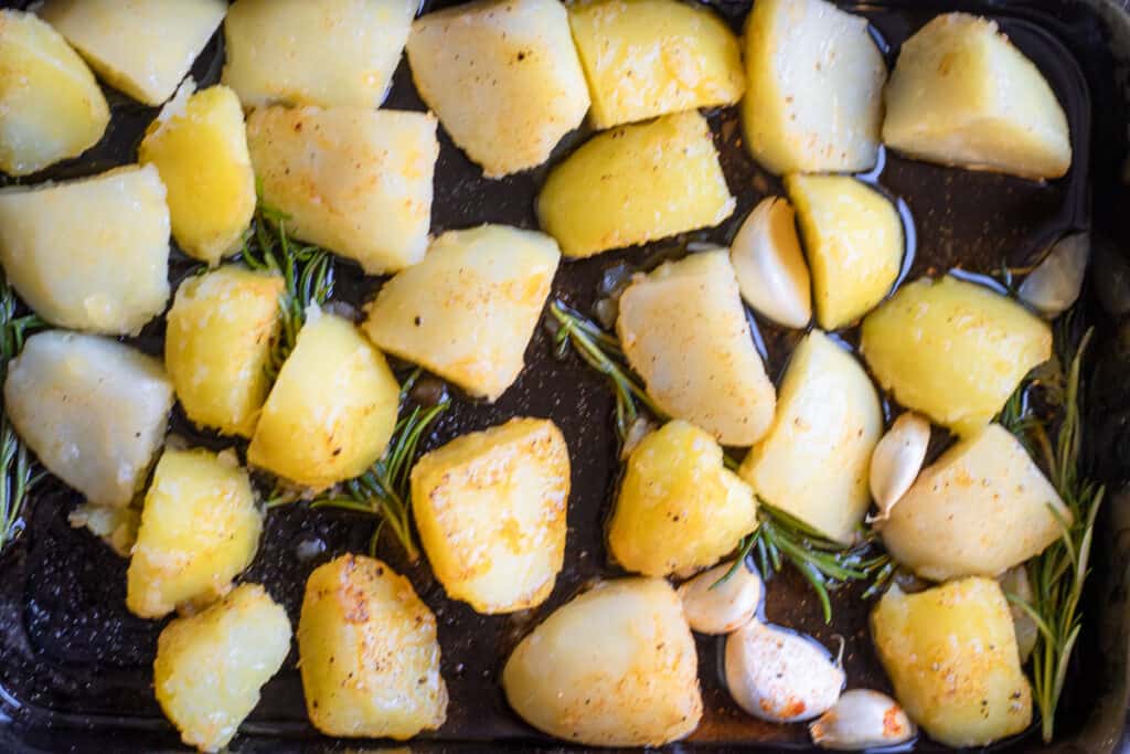 Par-boiled potatoes added to the hot duck fat in the tray.
