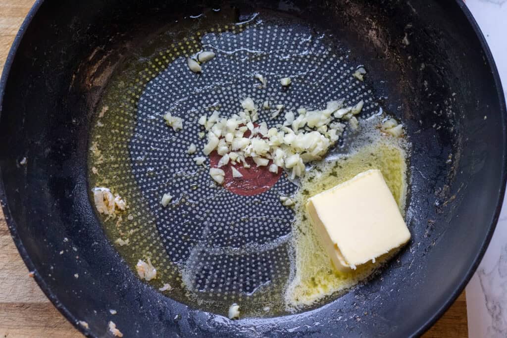 Melting the butter and cooking the garlic in a large pan.