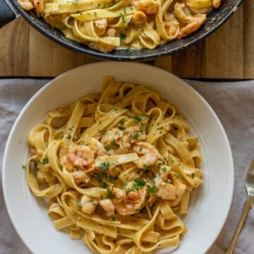 A serving bowl of the creamy shrimp pasta topped with parsley.