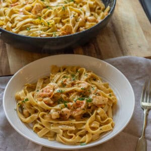Twirled fettuccine with seared shrimp in a white bowl.