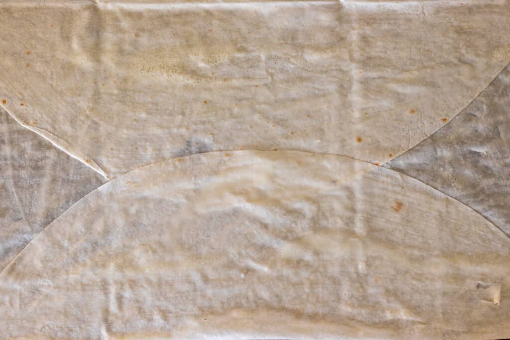 A round yufka sheet with two opposite sides folded in towards the middle.