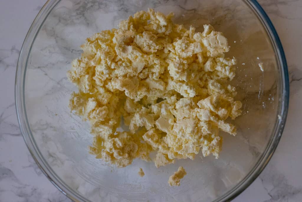 Crumbled feta cheese in a glass mixing bowl.