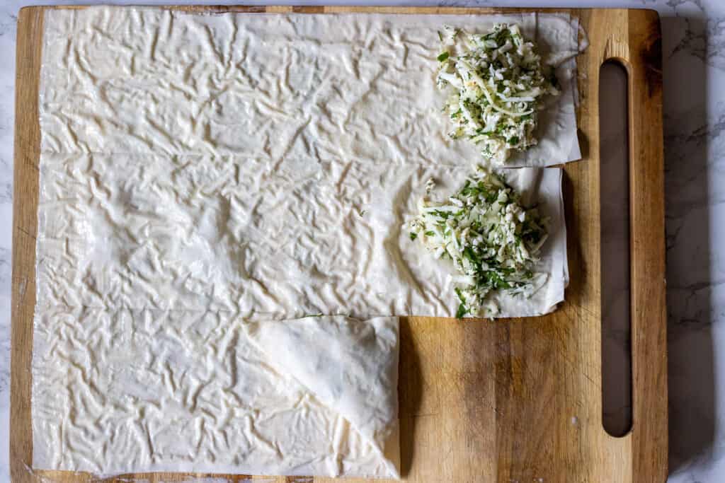 One phyllo triangle folded and finished while the remaining strips with filling wait to be folded.