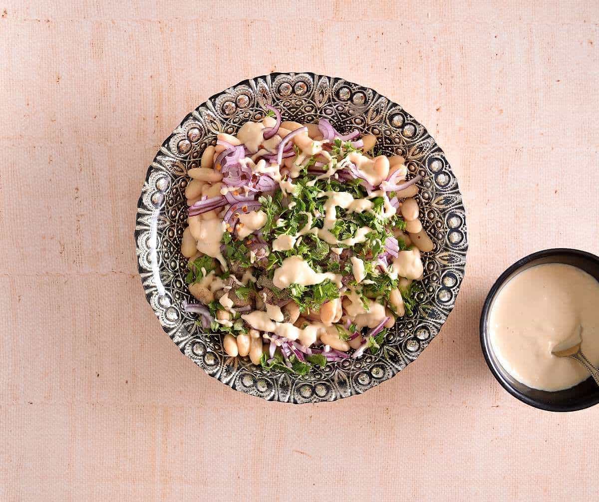 The bean salad is served with tahini sauce on the side.