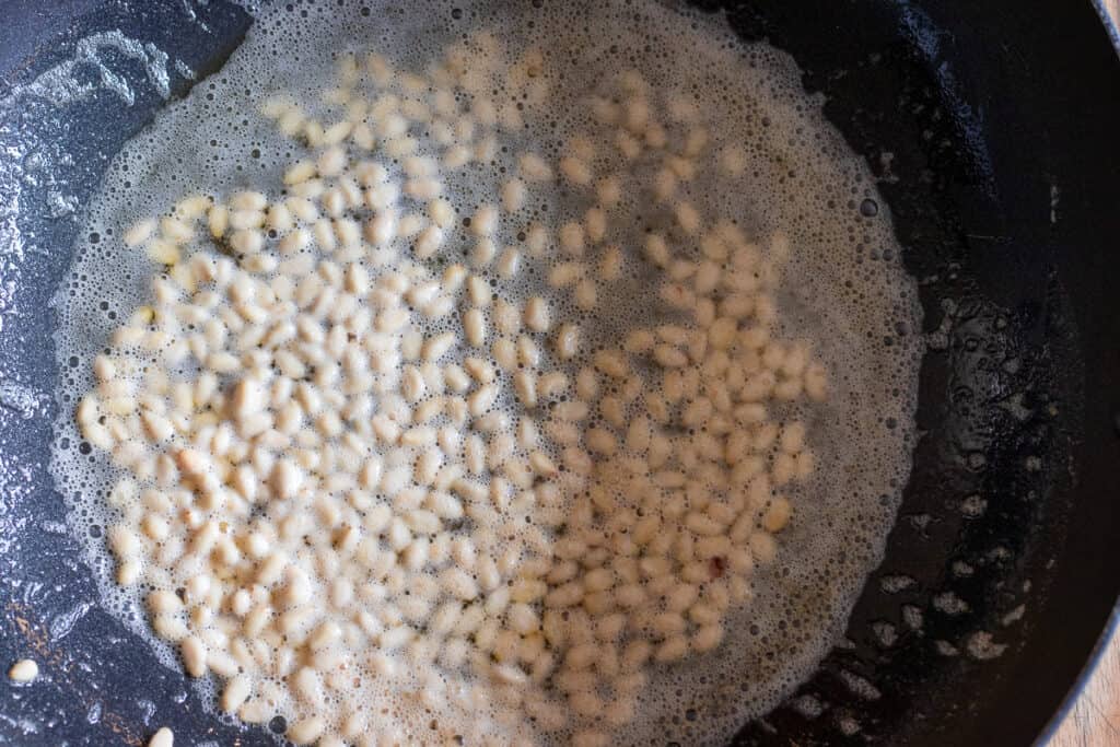 Sauté the pine nuts in butter