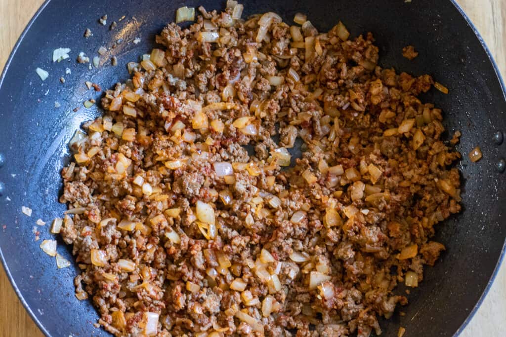 The tomato paste and chopped tomatoes are added to the pan.