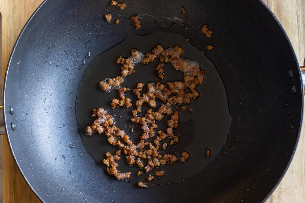 Rendering the lamb fat in a wok.