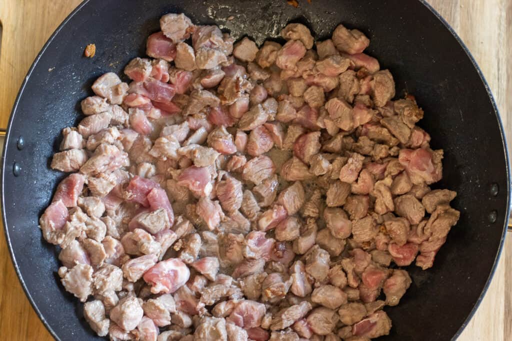 Sautéing the diced lamb with the rendered fat.