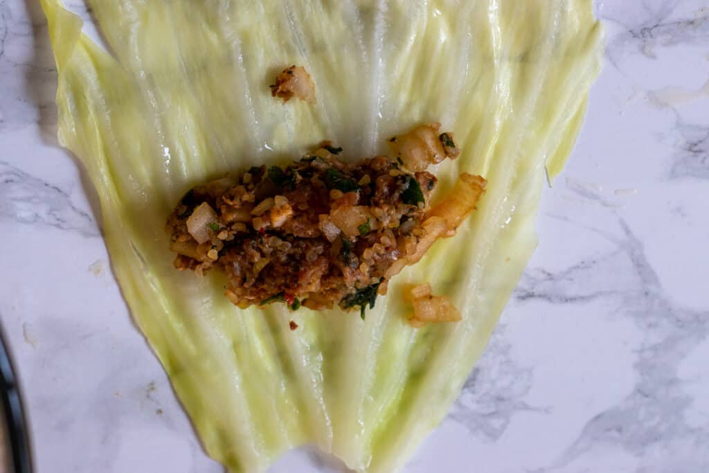 A spoonful of filling placed on a cabbage leaf.