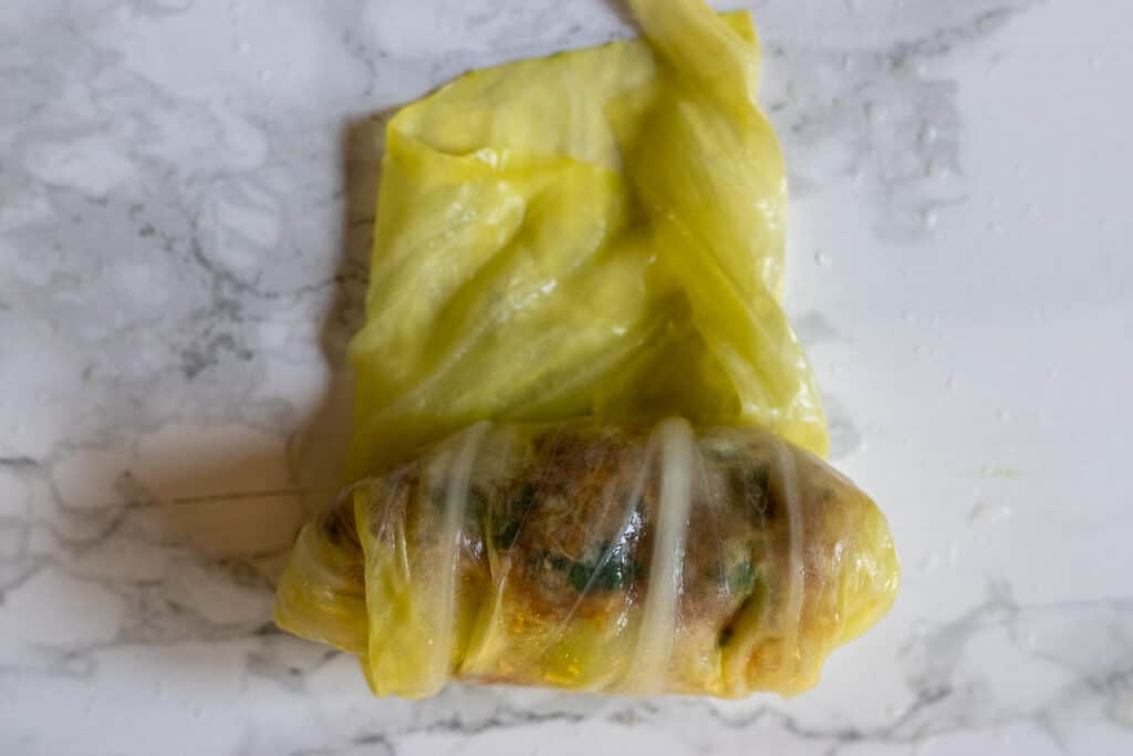 Tucking in the sides while rolling the cabbage leaf.