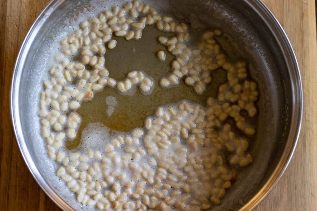 Sautéing the pine nuts with olive oil.