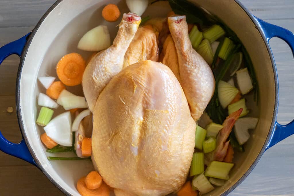 The chicken is placed in a pot with water and vegetables.