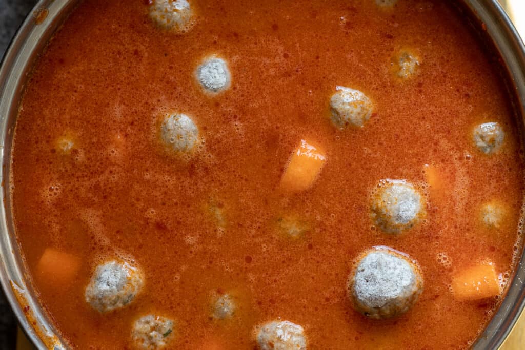 The meatballs and stock are added to the pan.