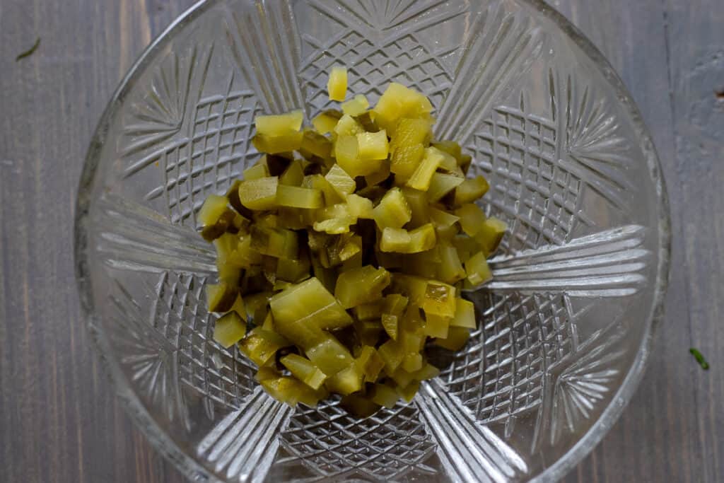 Finely diced cornichons on a wooden board.