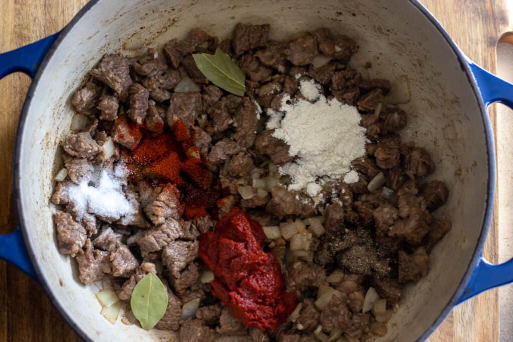 Flour, tomato paste, and spices stirred into the beef.